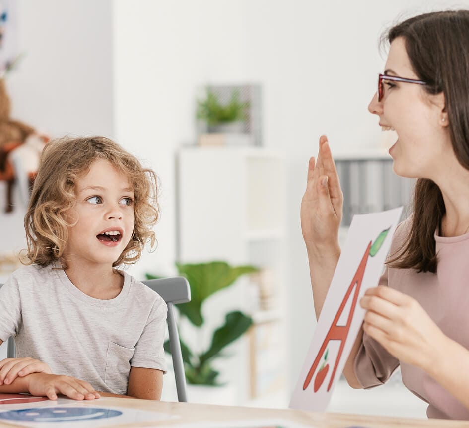 stock-photo-speech-therapist-teaching-letter-pronunciation-to-a-young-boy-in-a-classroom-1162402759 (2) 2